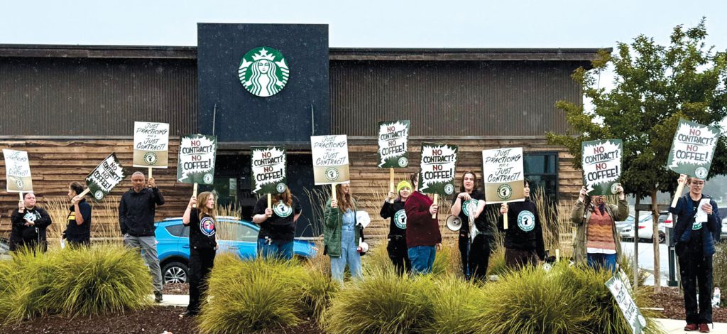 Starbucks baristas hold signs and chant