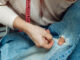 Bringing the art of repair back to the community A woman mends jeans, sews a patch on a hole, hands close-up